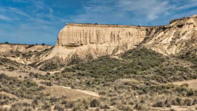 Towering sandstone rock formations rising from a Saharan desert landscape under a clear blue sky
