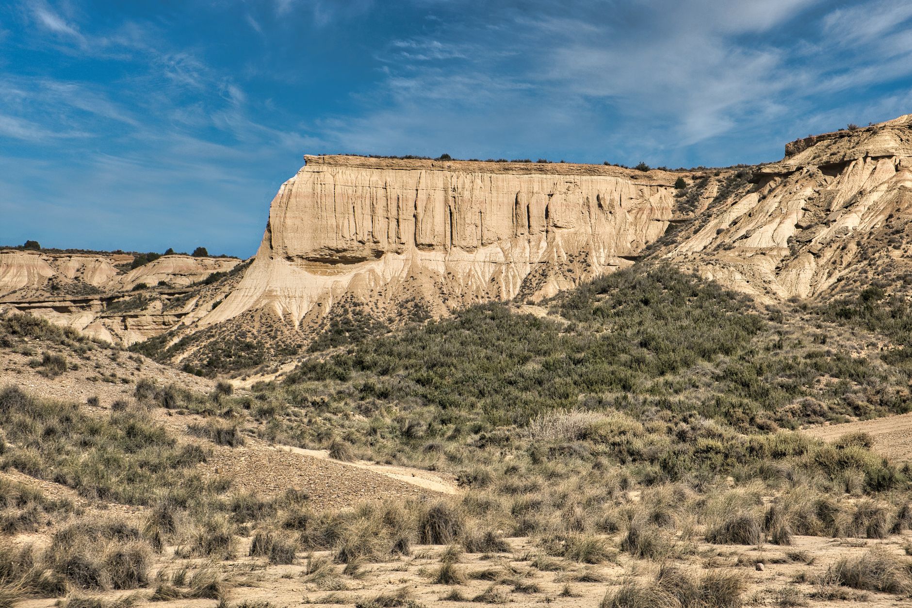 Towering sandstone rock formations rising from a Saharan desert landscape under a clear blue sky