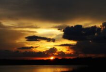 Wide view of a calm African lake at sunset with mountains visible in the distance