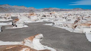 White chalk rock formations rising from a flat desert plain under a clear blue sky