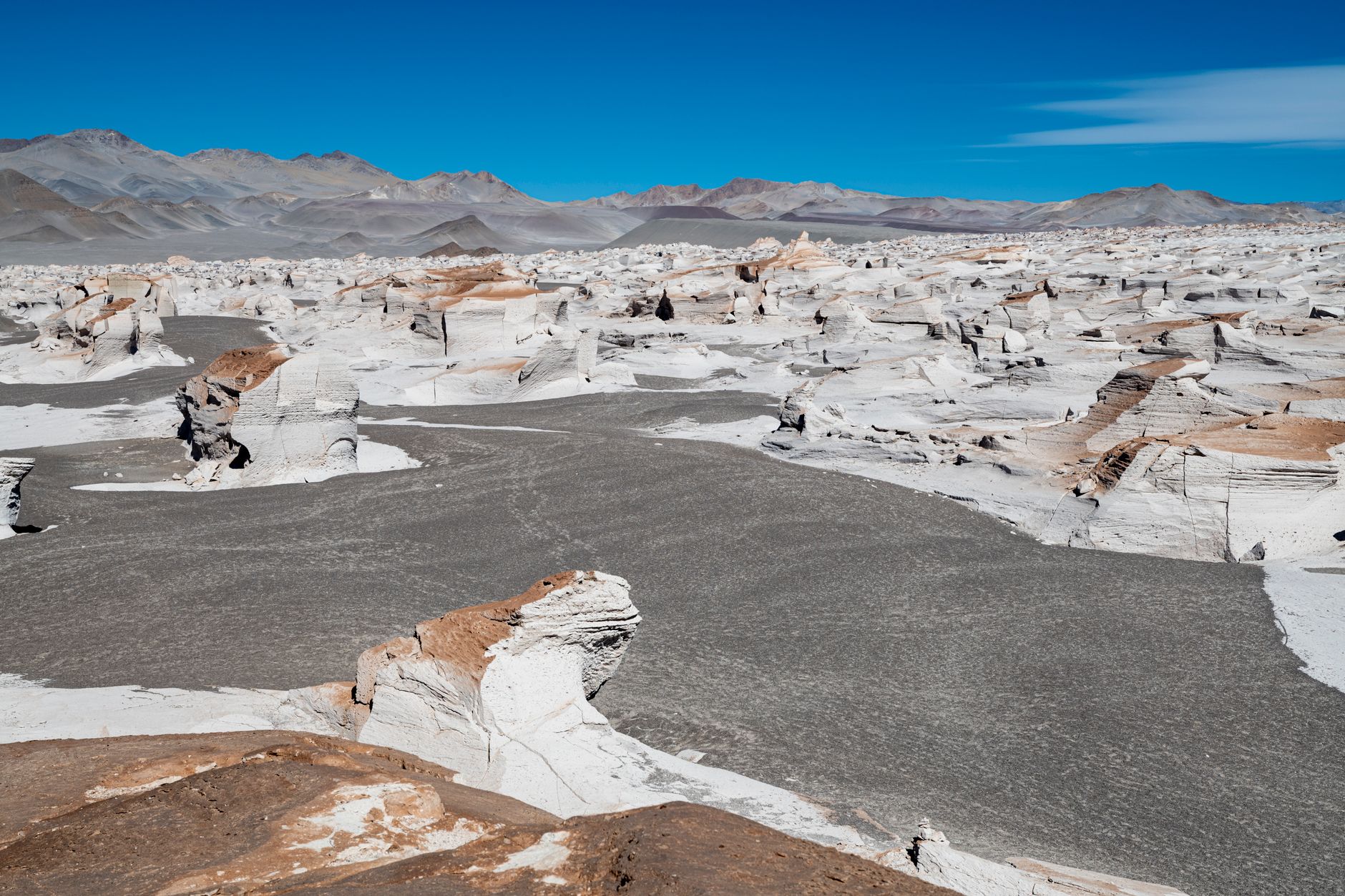 White chalk rock formations rising from a flat desert plain under a clear blue sky