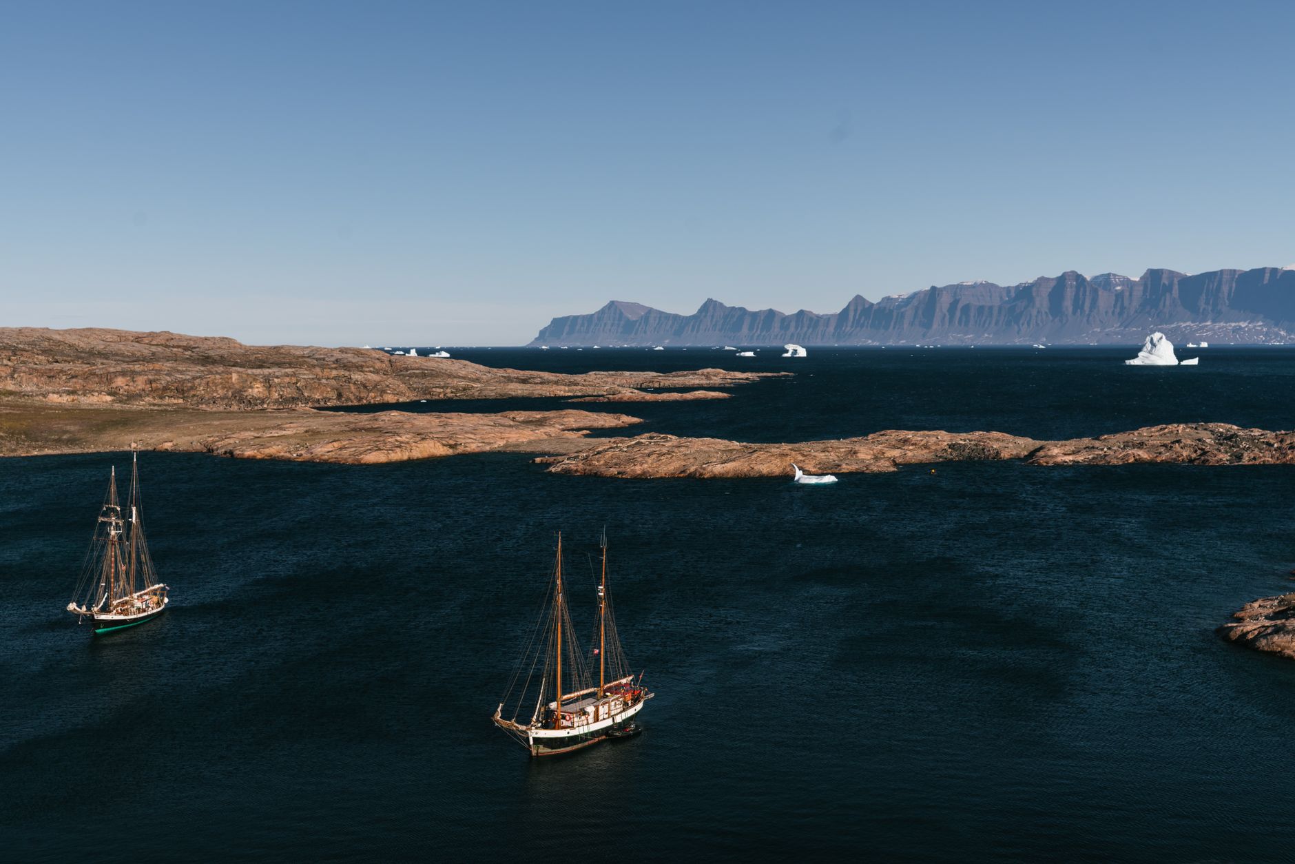 Massive icebergs floating in a calm Arctic fjord under soft daylight near Ilulissat, Greenland