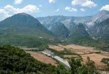 Wide view of a glacially carved alpine valley with turquoise river and forested peaks in the Albanian Alps