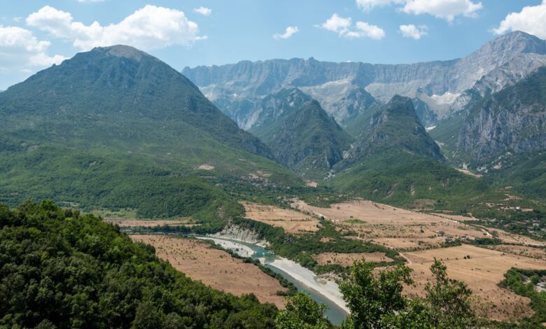 Wide view of a glacially carved alpine valley with turquoise river and forested peaks in the Albanian Alps