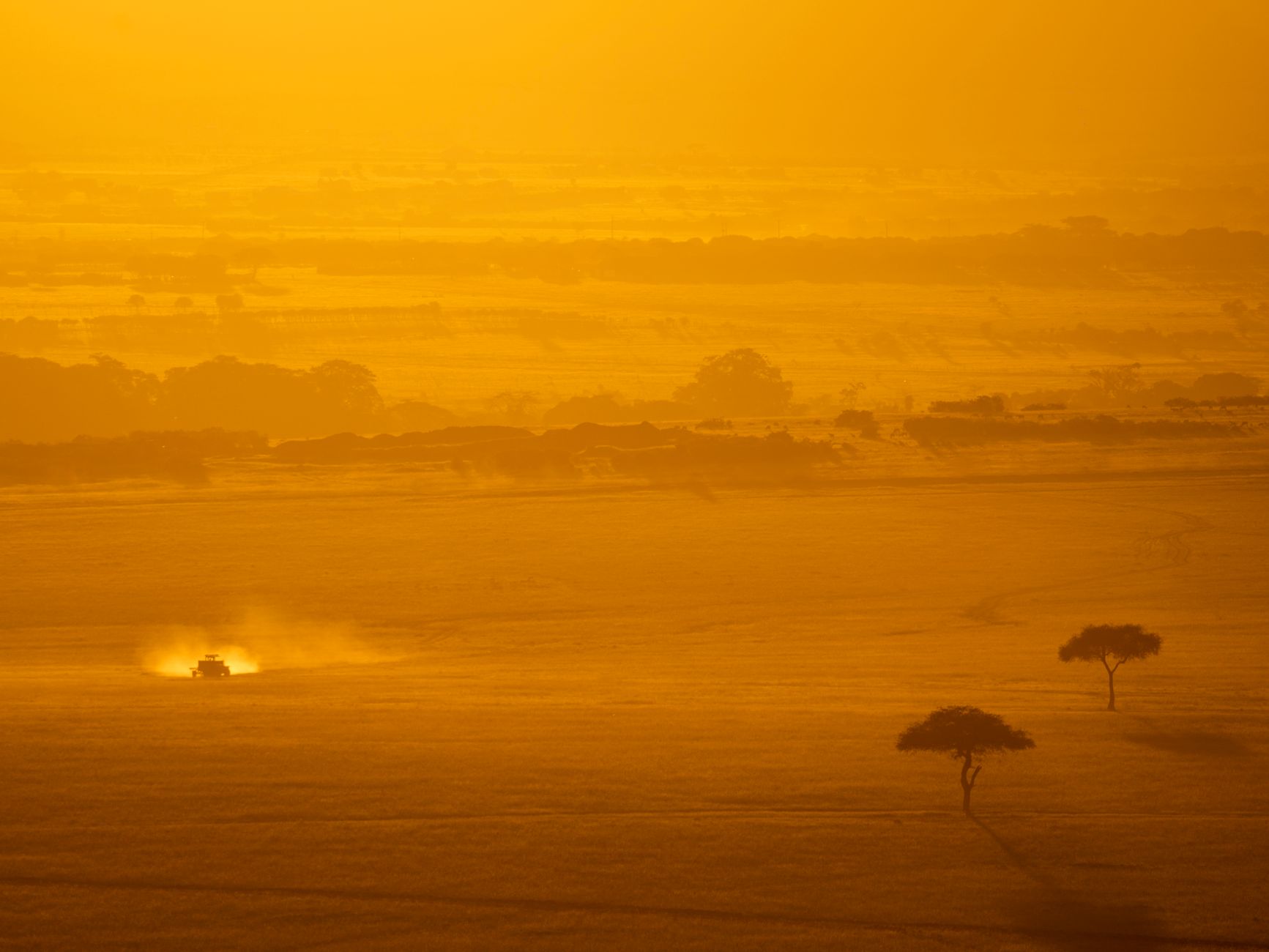 Wide open savanna landscape typical of Kenya's Laikipia Plateau with acacia trees and dry grassland
