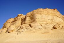 Wide red sandstone formations under clear blue sky in Wadi Rum desert landscape