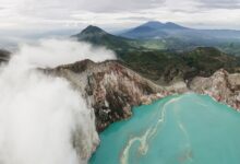 Aerial view of a turquoise volcanic crater lake surrounded by steep Andean ridgelines