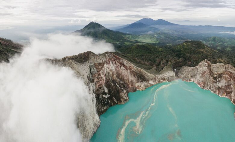 Aerial view of a turquoise volcanic crater lake surrounded by steep Andean ridgelines