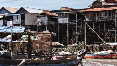 Wooden stilt houses built over a calm lake with misty mountains in the background