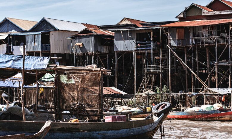 Wooden stilt houses built over a calm lake with misty mountains in the background