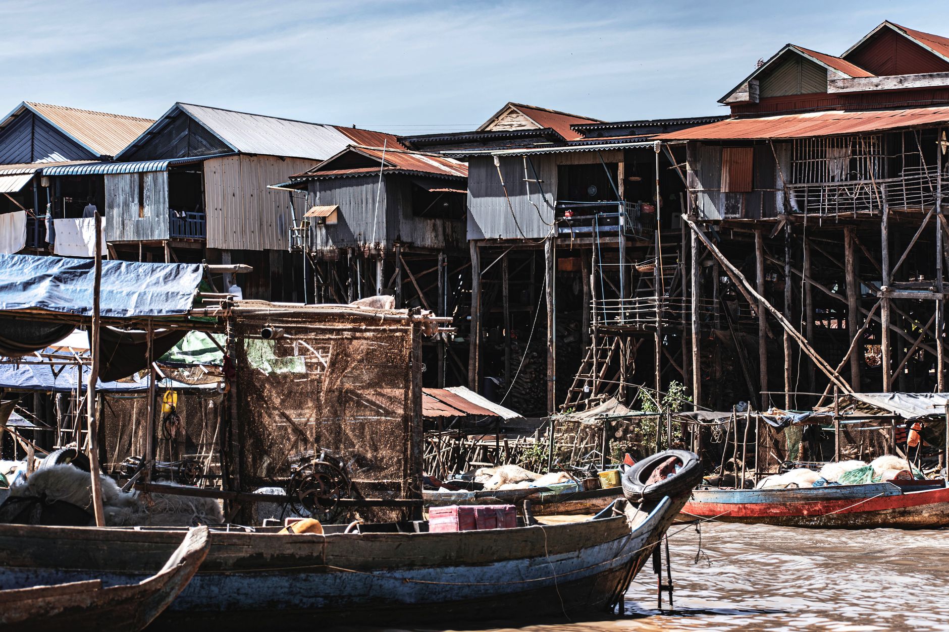 Wooden stilt houses built over a calm lake with misty mountains in the background