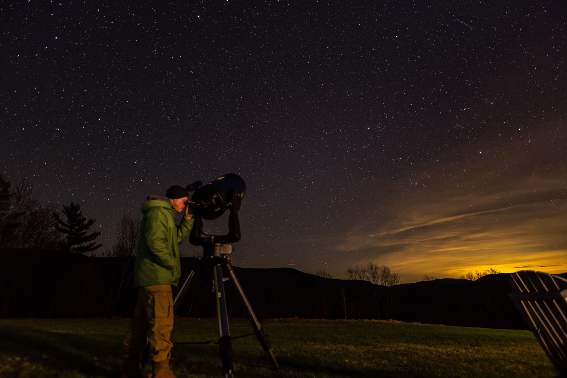 Person using a telescope to observe stars in a dark remote location