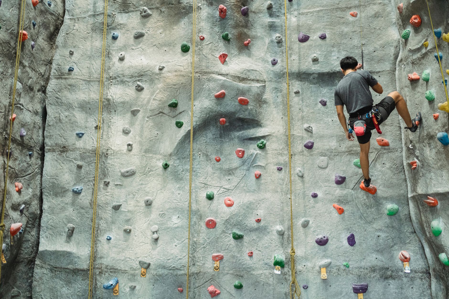 Climber ascending a vertical limestone face on a bolted sport climbing route