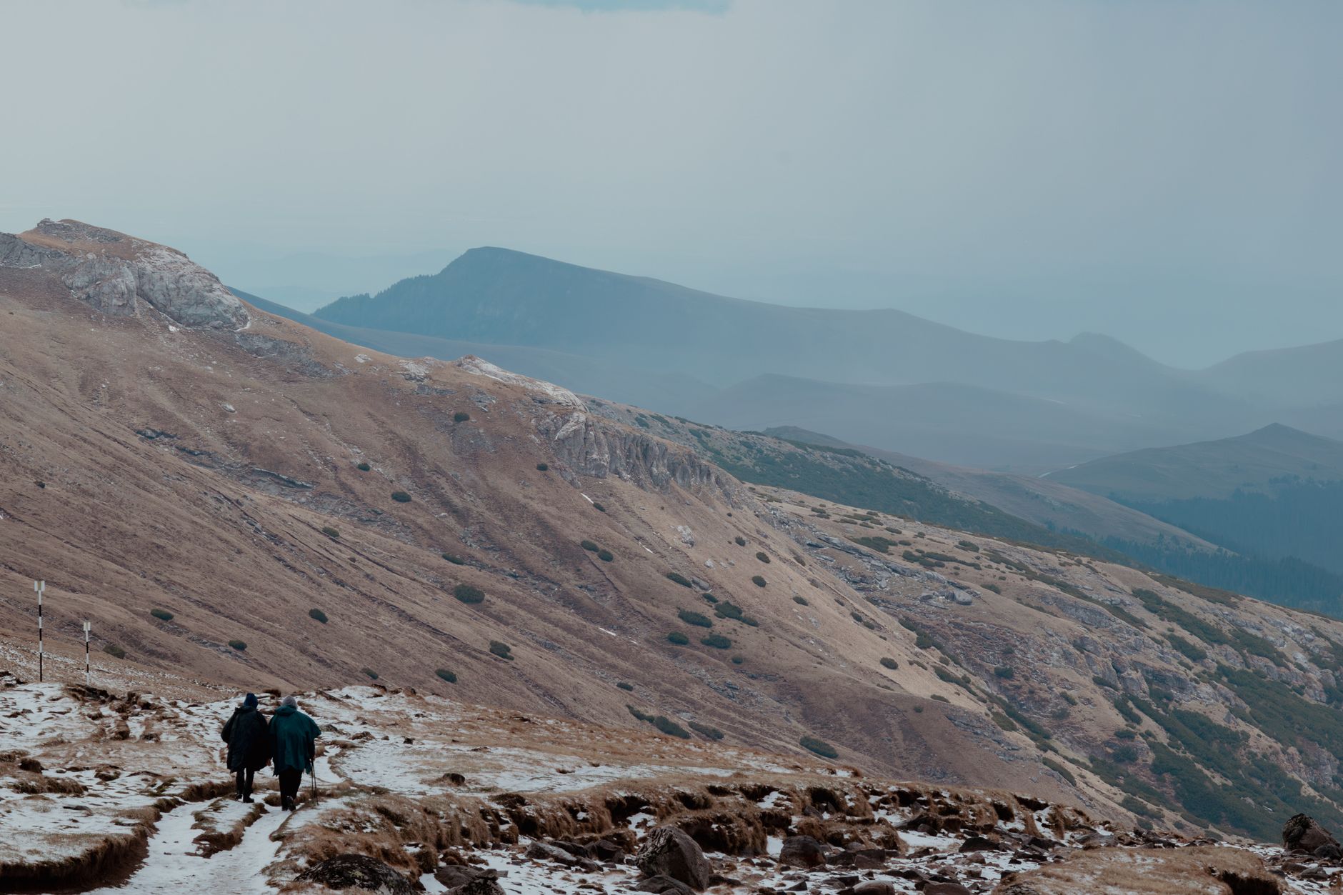 Solo trekker walking along a high-altitude trail with dramatic peaks in the background
