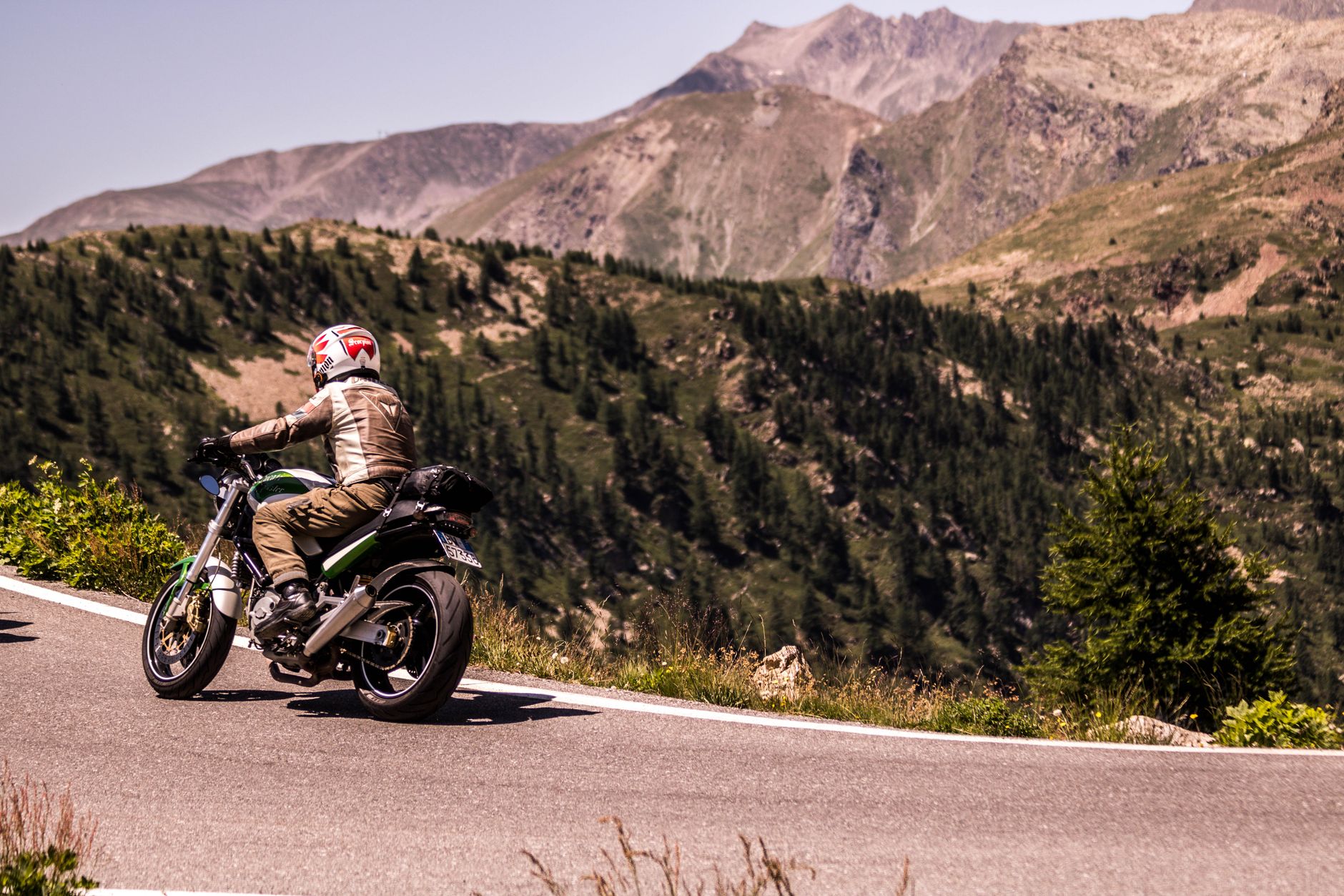 Motorcycle rider navigating a narrow mountain pass with dramatic valley views below