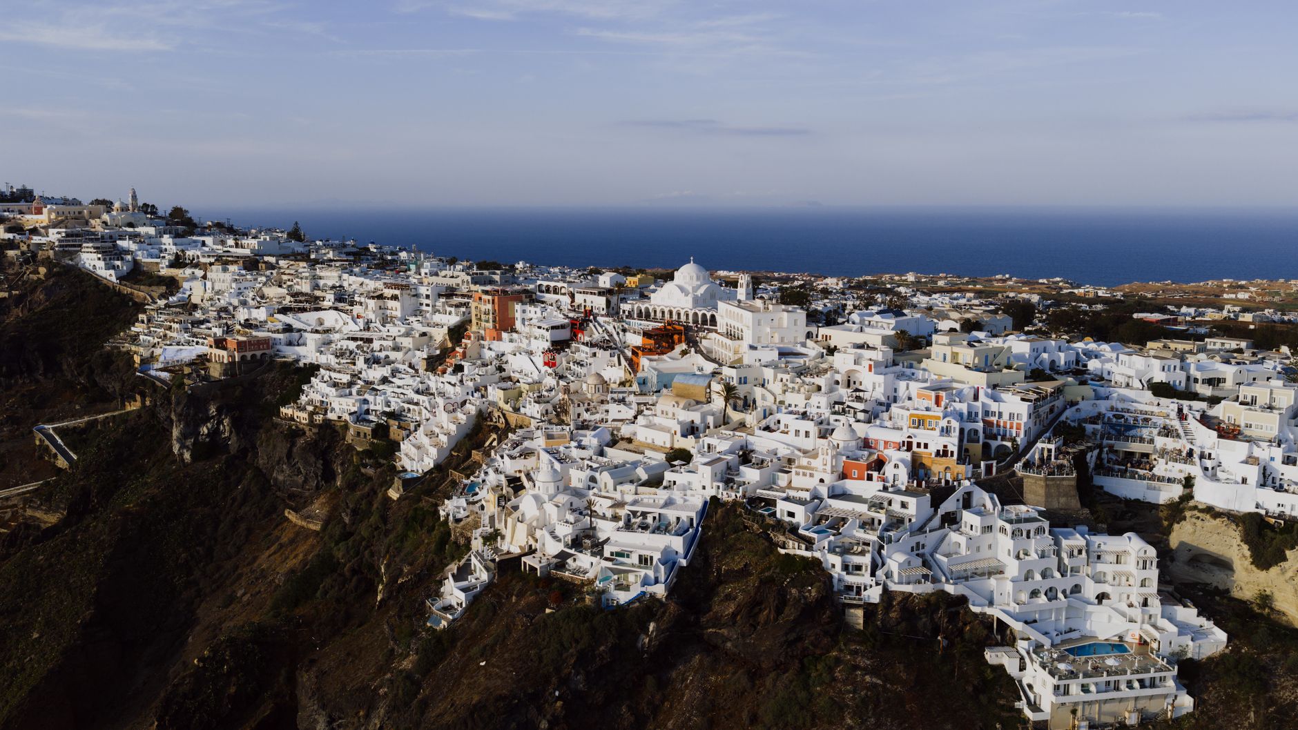 A whitewashed hilltop village with medieval walls overlooking a wide, flat landscape