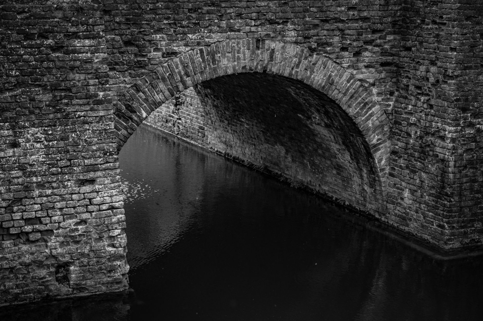 Historic multi-arch stone bridge spanning a calm river at dusk with warm evening light