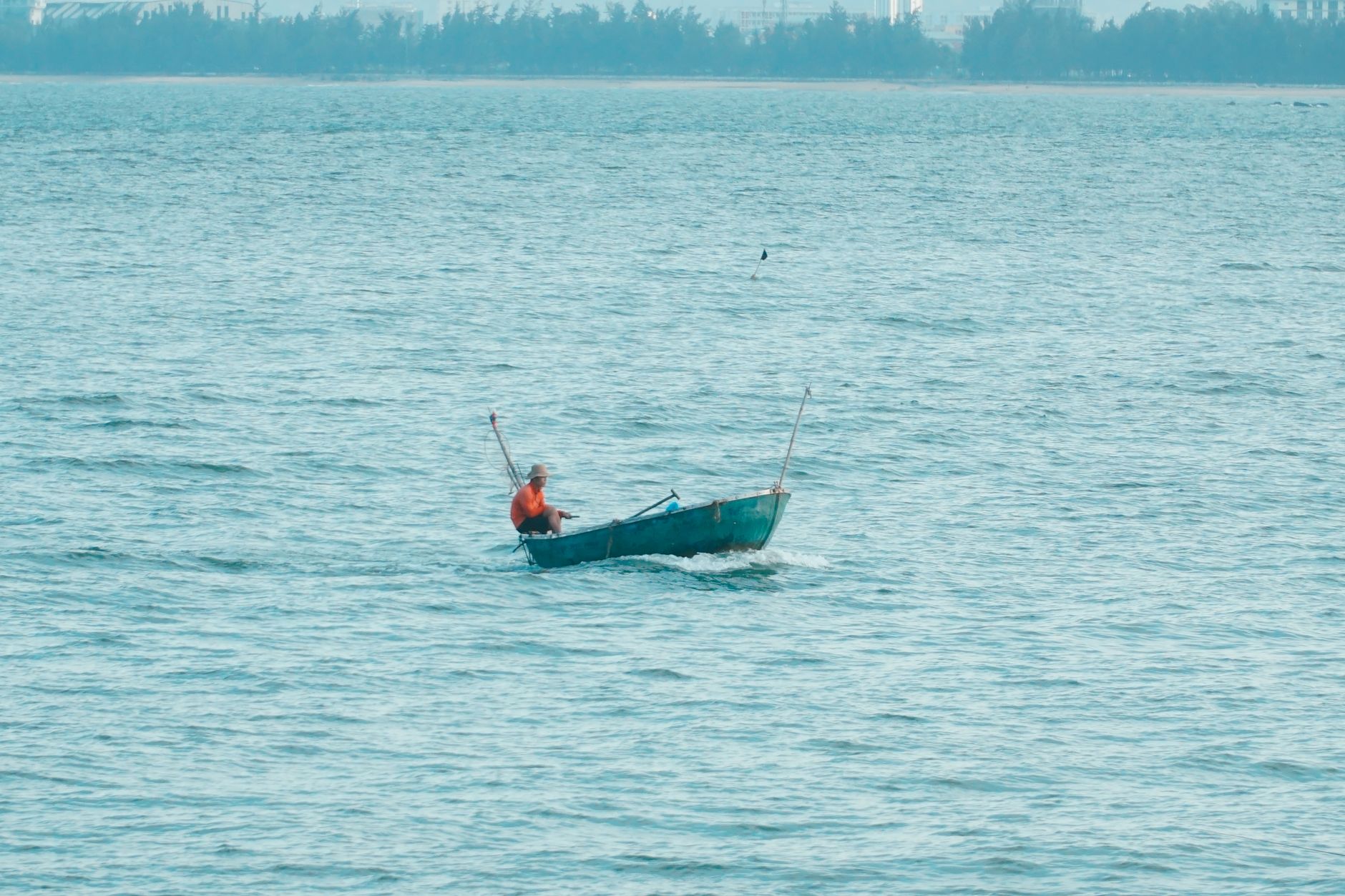 Traditional fisherman balancing on wooden boat while casting net on still water