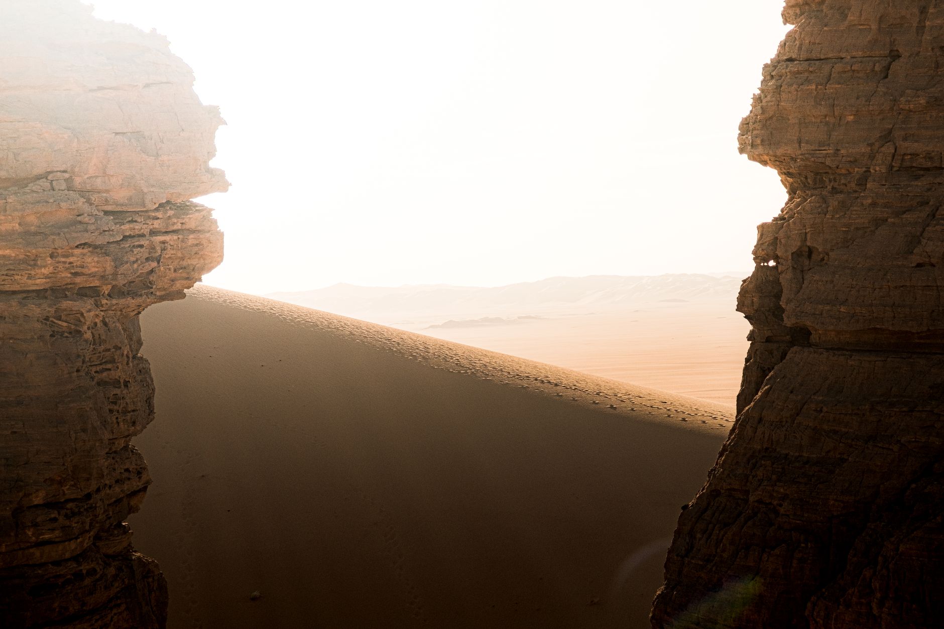 Wide view of a dramatic desert gorge with towering sandstone and limestone cliffs under clear sky