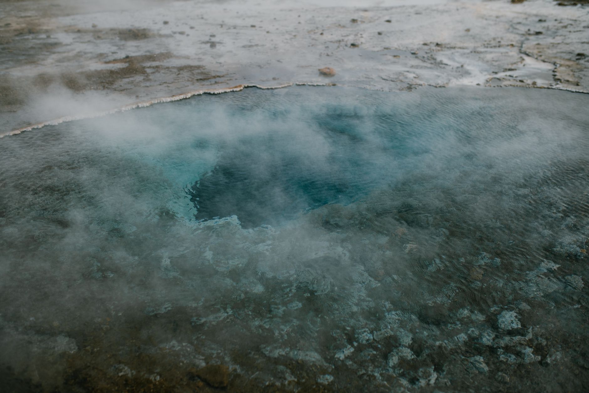 Small natural geothermal pool at the edge of a rocky Icelandic coastline