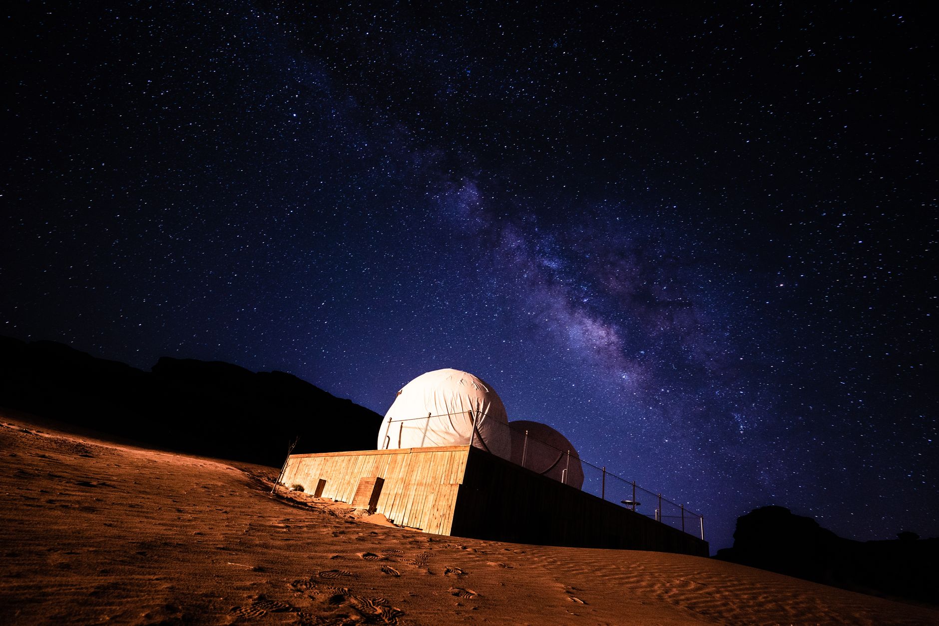 A clear night sky filled with stars above a desert landscape with rocky silhouettes