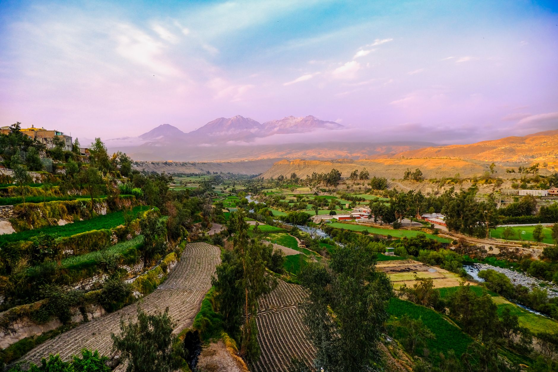 Sunrise over a high-altitude Andean landscape with misty mountain peaks in the distance