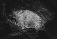 Rocky cave entrance in a forested mountain landscape in Romania