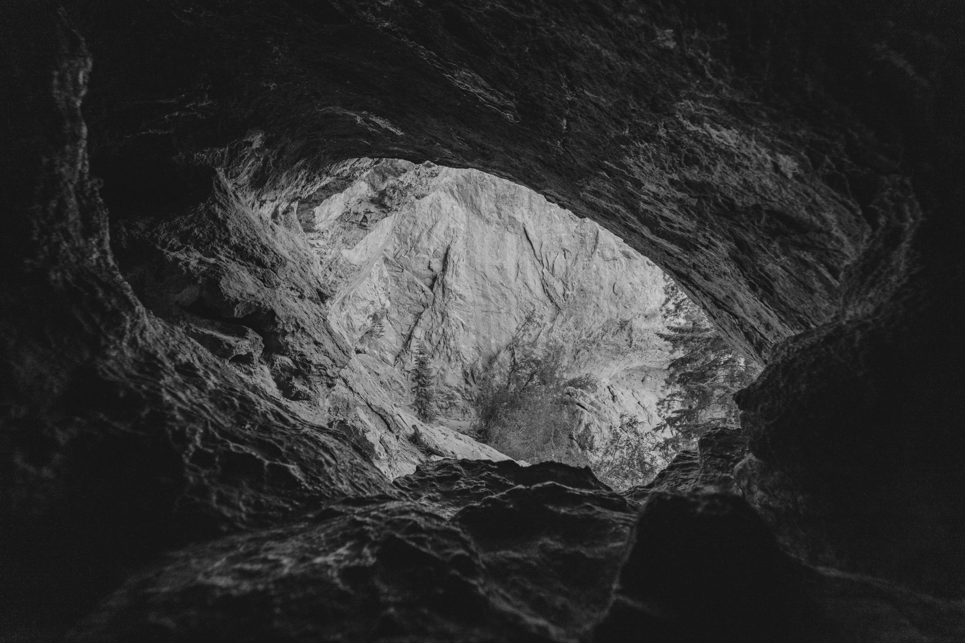 Rocky cave entrance in a forested mountain landscape in Romania
