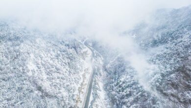 A narrow mountain road disappearing into thick cloud and fog on a steep Andean slope