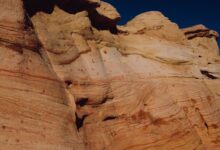 Towering sandstone rock formations rising from a desert plateau under a clear blue sky