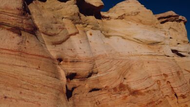 Towering sandstone rock formations rising from a desert plateau under a clear blue sky