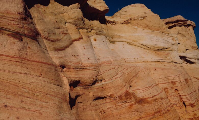 Towering sandstone rock formations rising from a desert plateau under a clear blue sky