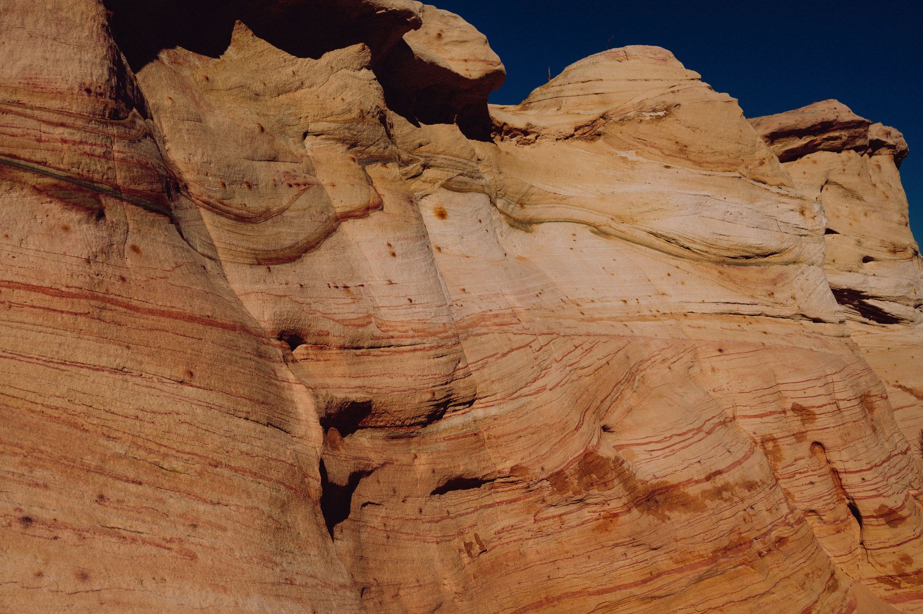 Towering sandstone rock formations rising from a desert plateau under a clear blue sky