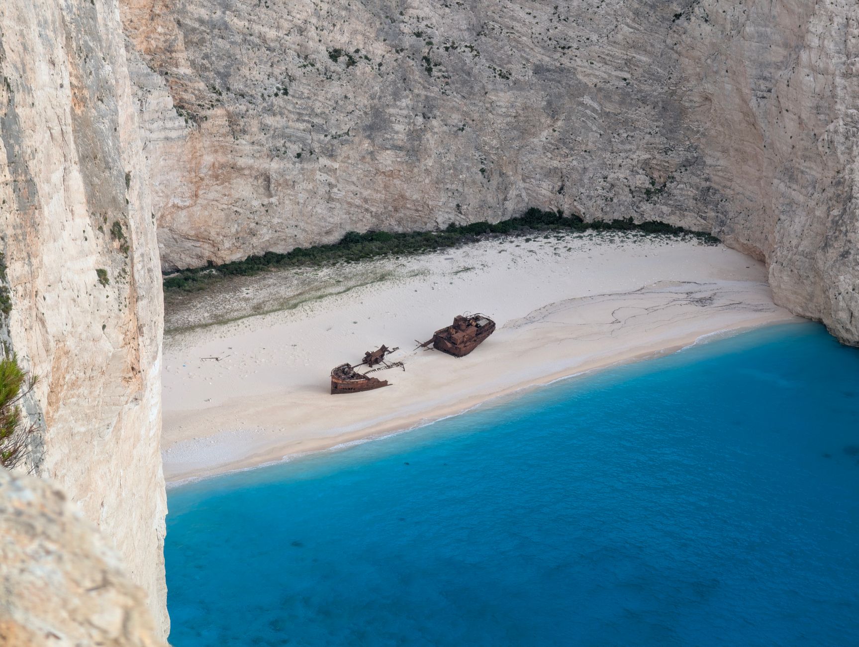 A rusted shipwreck sitting on a remote Atlantic coastline with desert sand dunes in the background