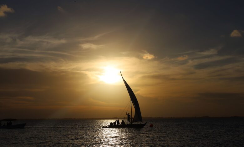 A traditional wooden dhow sailing on calm Indian Ocean waters near an archipelago coastline