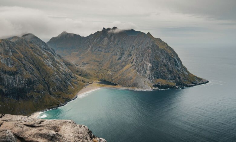 Dramatic rocky coastline meeting a calm sea under a wide blue sky