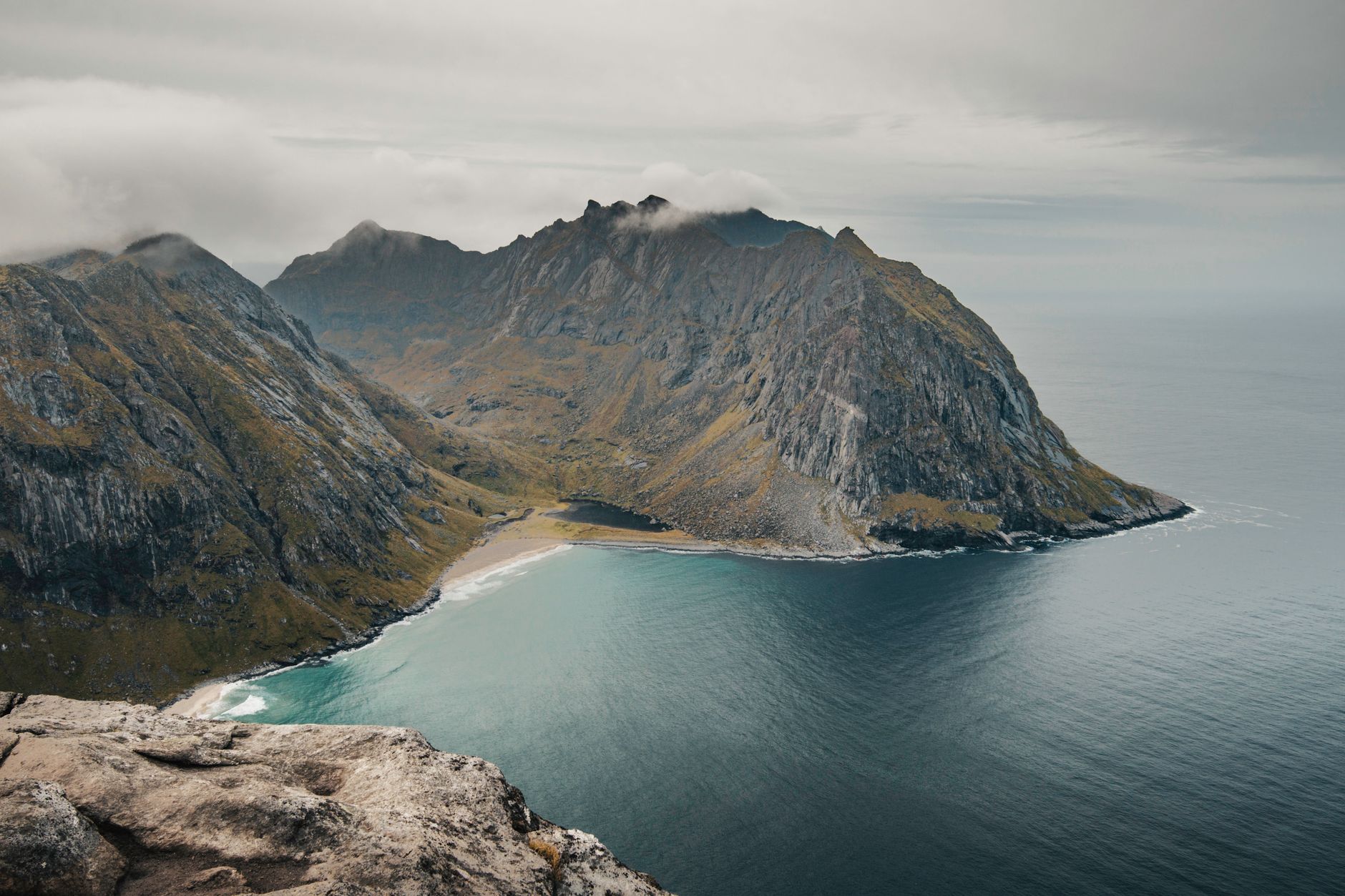 Dramatic rocky coastline meeting a calm sea under a wide blue sky