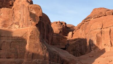Towering red sandstone rock formations rising from the flat desert floor of Wadi Rum, Jordan