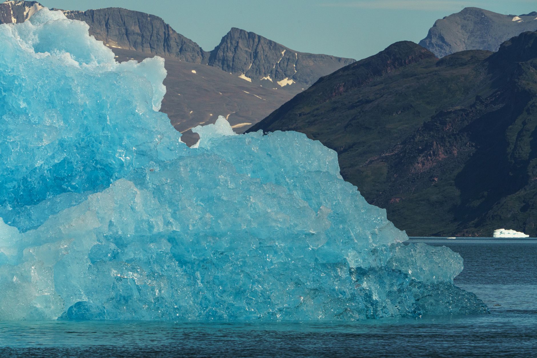 Wide aerial view of a deep Arctic fjord surrounded by snow-capped cliffs and icebergs