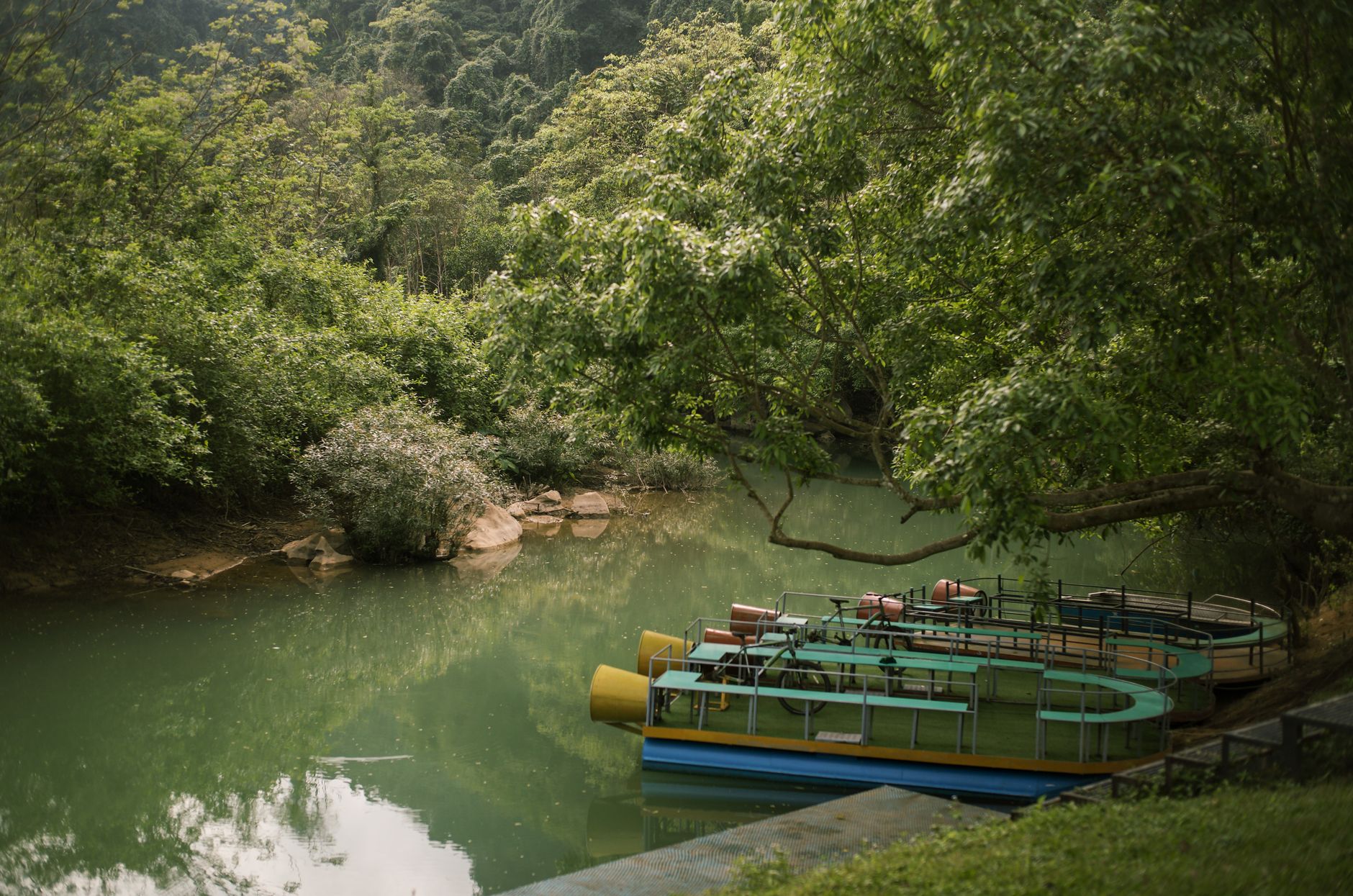 A small wooden boat traveling along a calm jungle river surrounded by dense green vegetation
