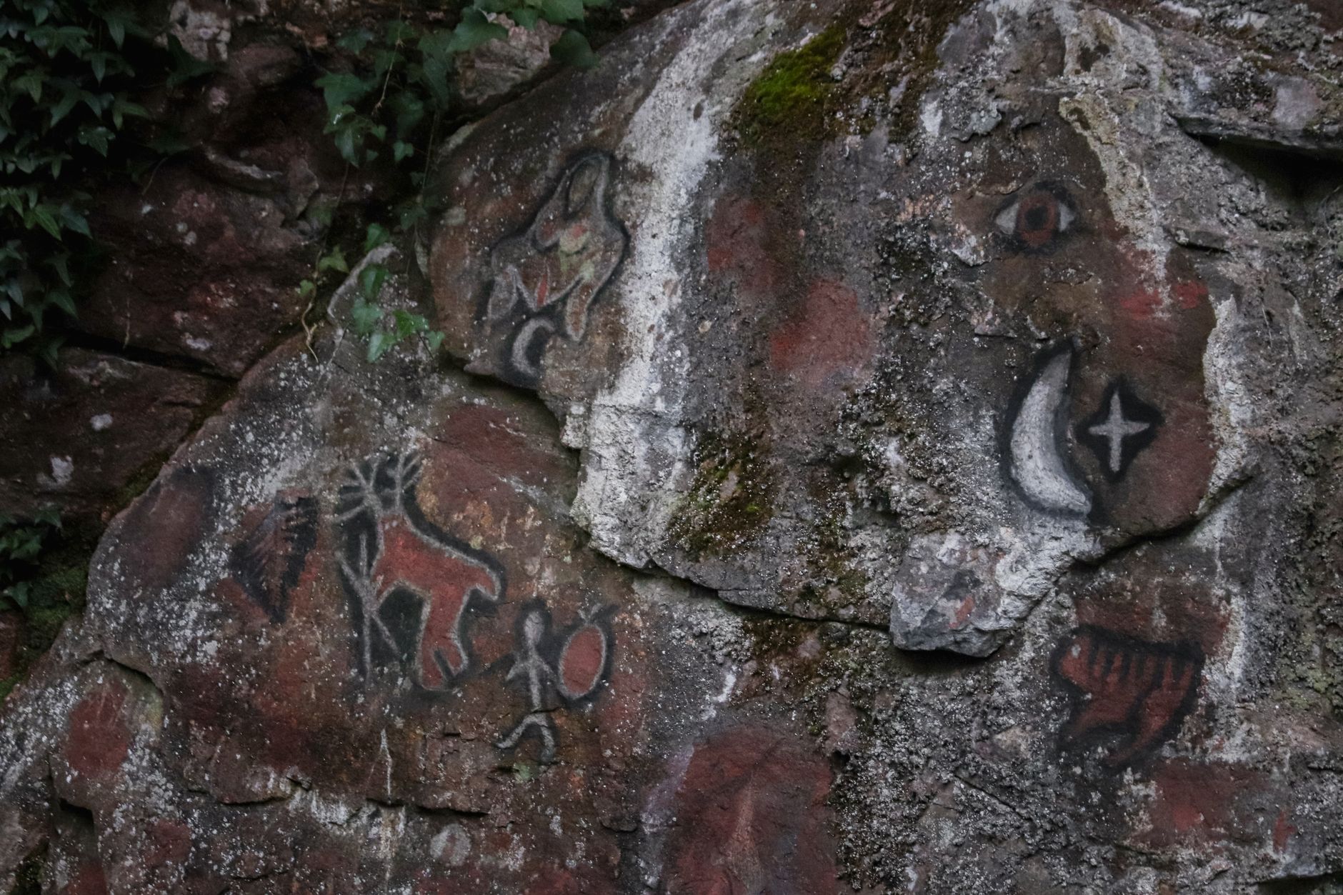 Ancient rock paintings covering a weathered stone wall inside a desert cave shelter