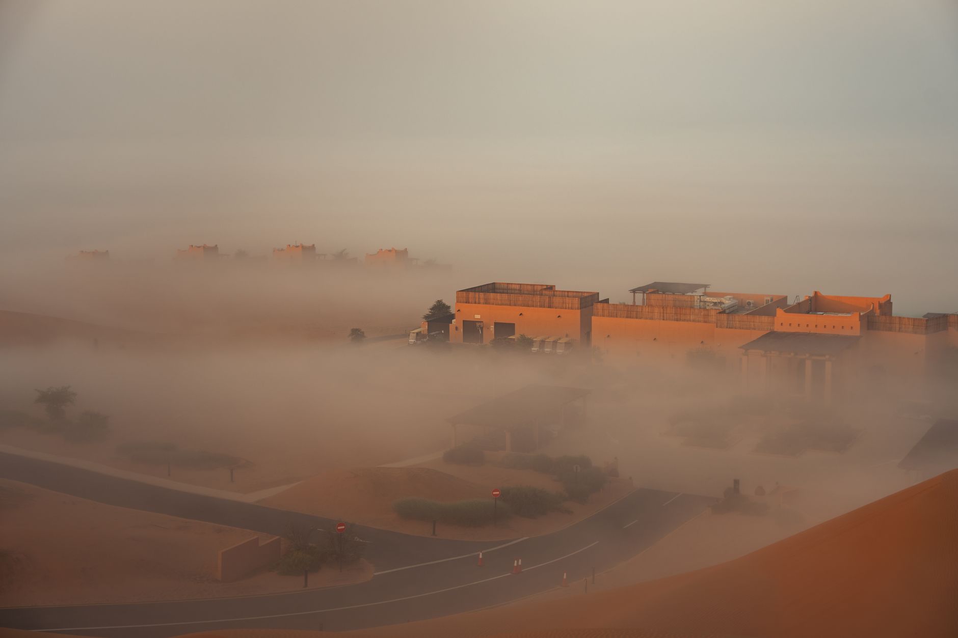 Dense ocean fog rolling over a desert shoreline with rocky terrain and crashing Atlantic waves