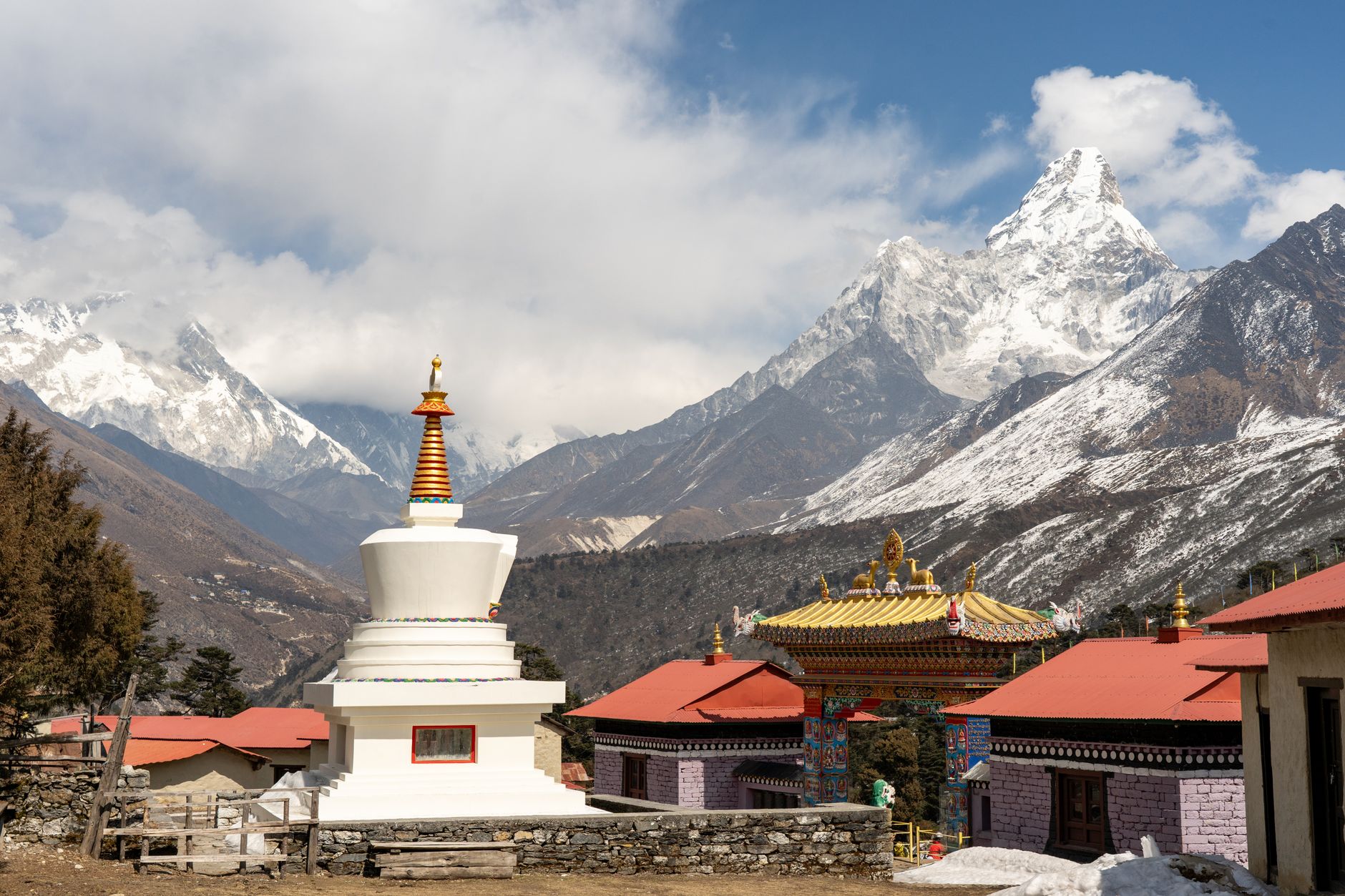 Ancient Buddhist monastery with white walls set against a dramatic Himalayan mountain backdrop