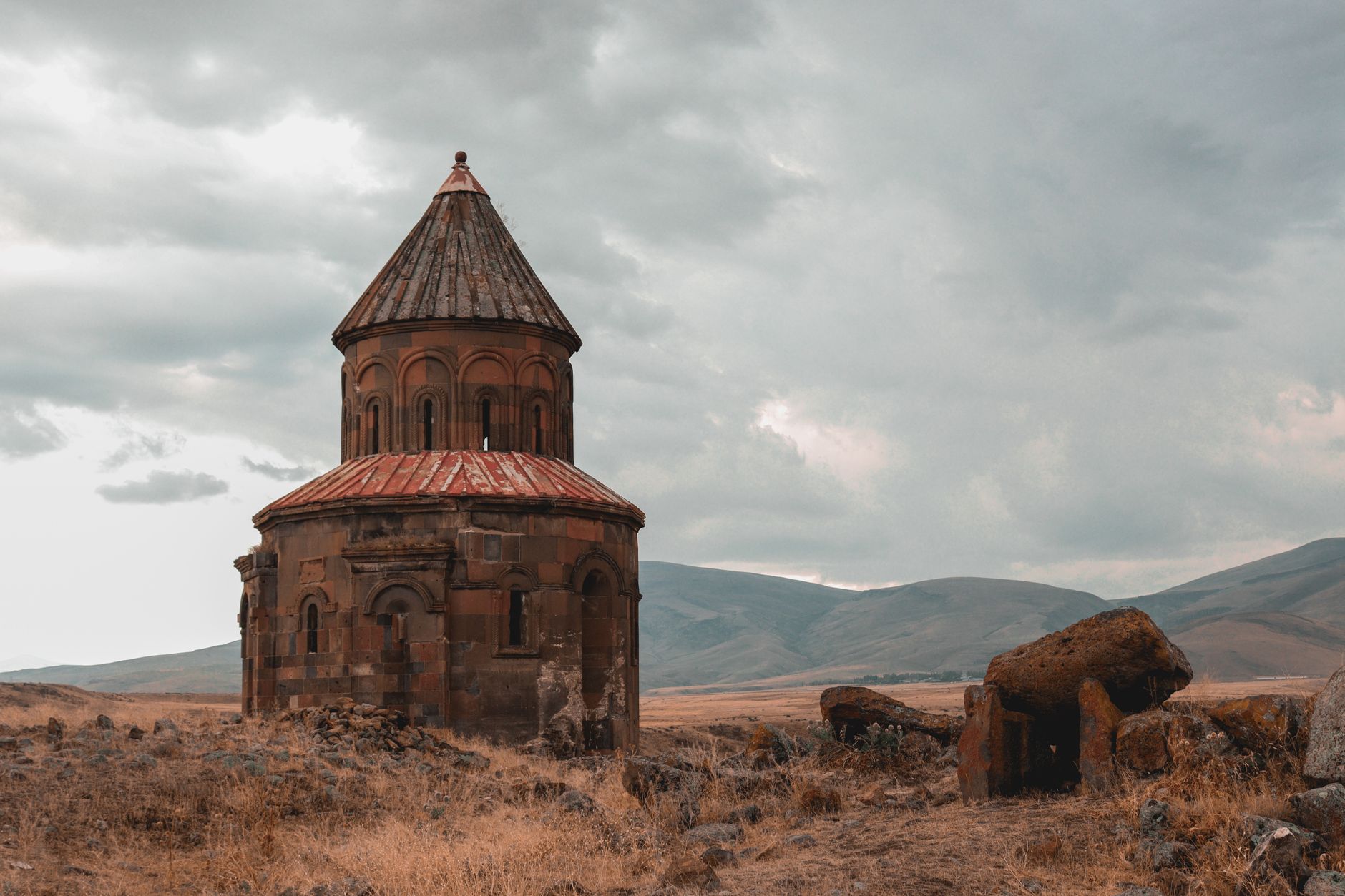 Interior of an ancient Armenian stone church with carved khachkars and dim natural light