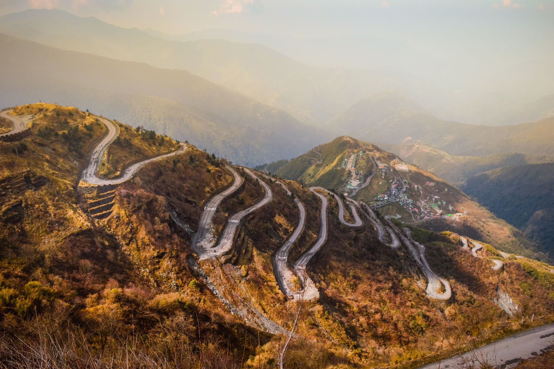 Narrow winding road through stark Himalayan terrain under a clear blue sky at high altitude