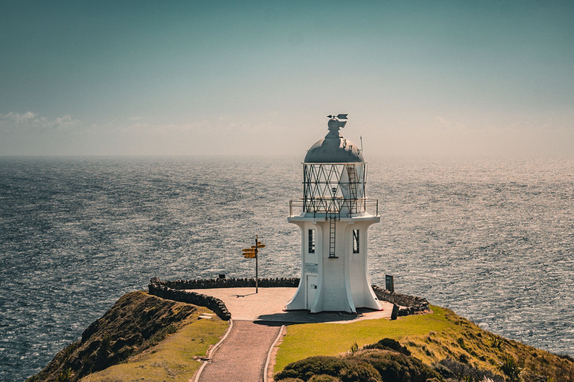 A lighthouse standing on a dramatic coastal headland above crashing ocean waves