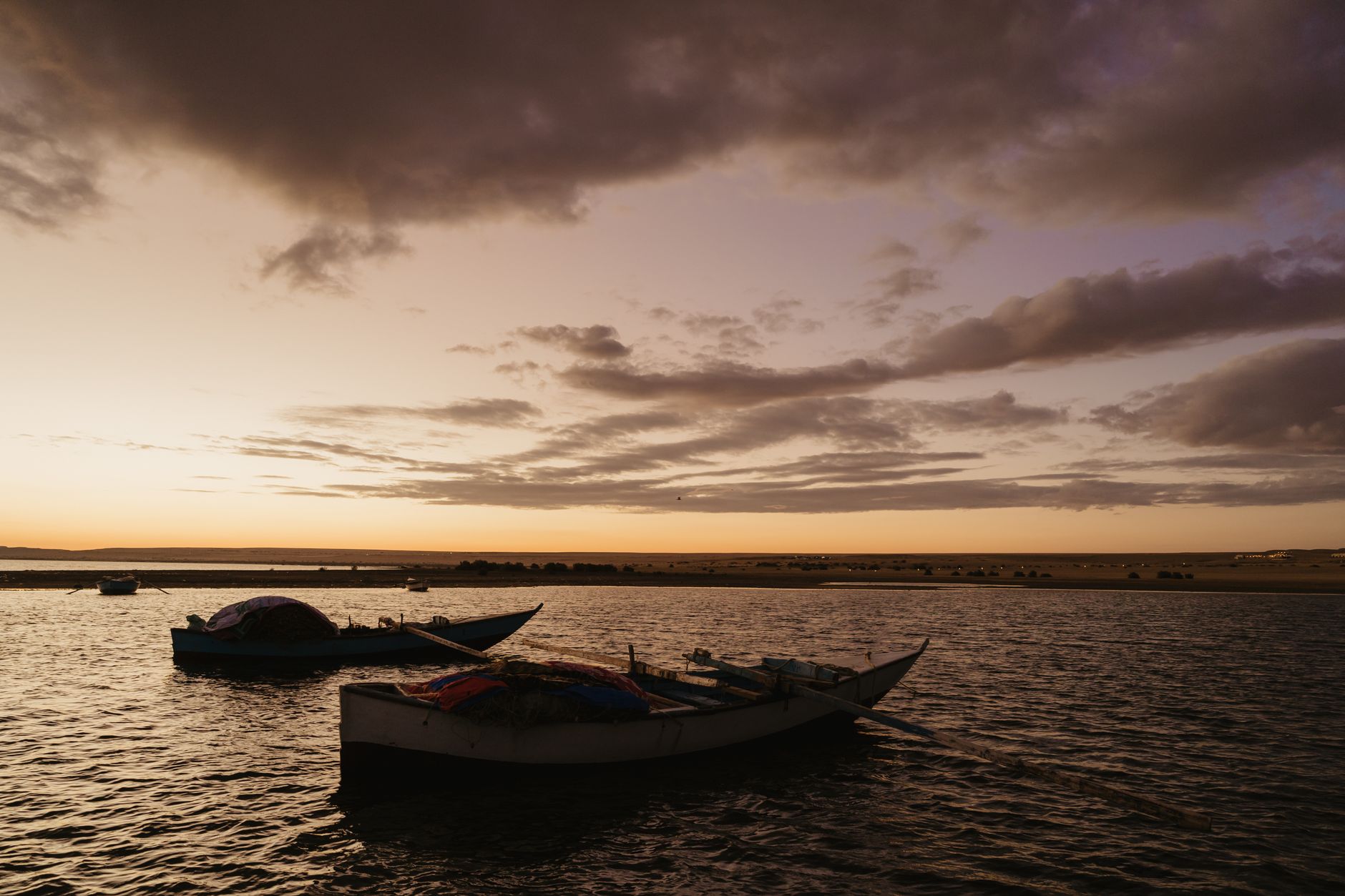 A vivid orange sunset reflected on the calm surface of Lake Tanganyika with distant mountains on the horizon