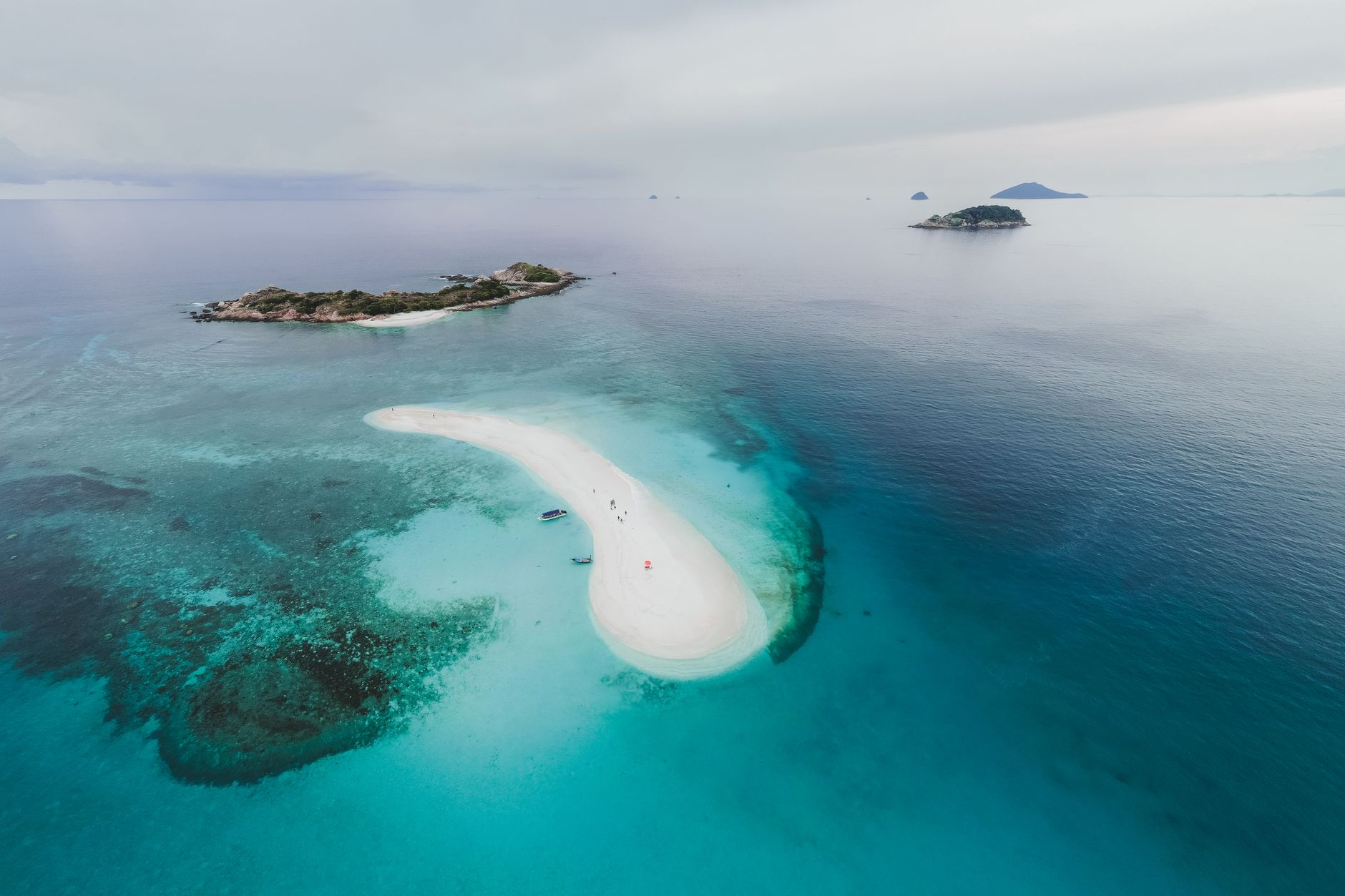 Aerial view of a small tropical island surrounded by turquoise shallow water