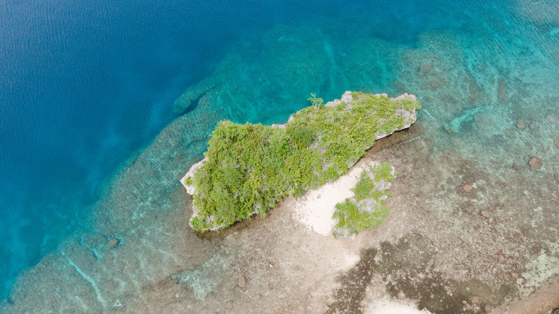 Aerial view of a small remote island surrounded by shallow turquoise water