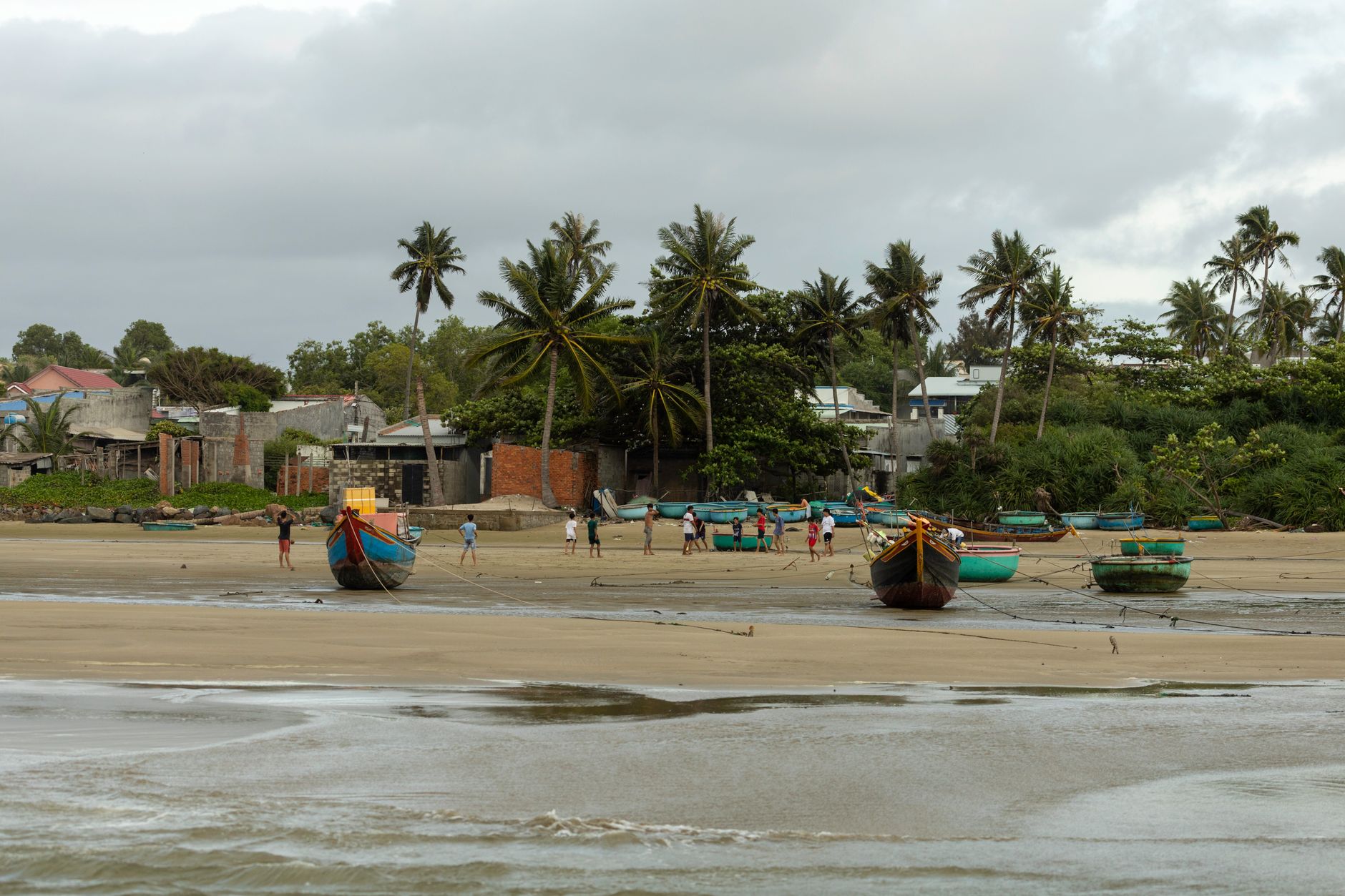 Wooden fishing boats moored near a small coastal village at dawn